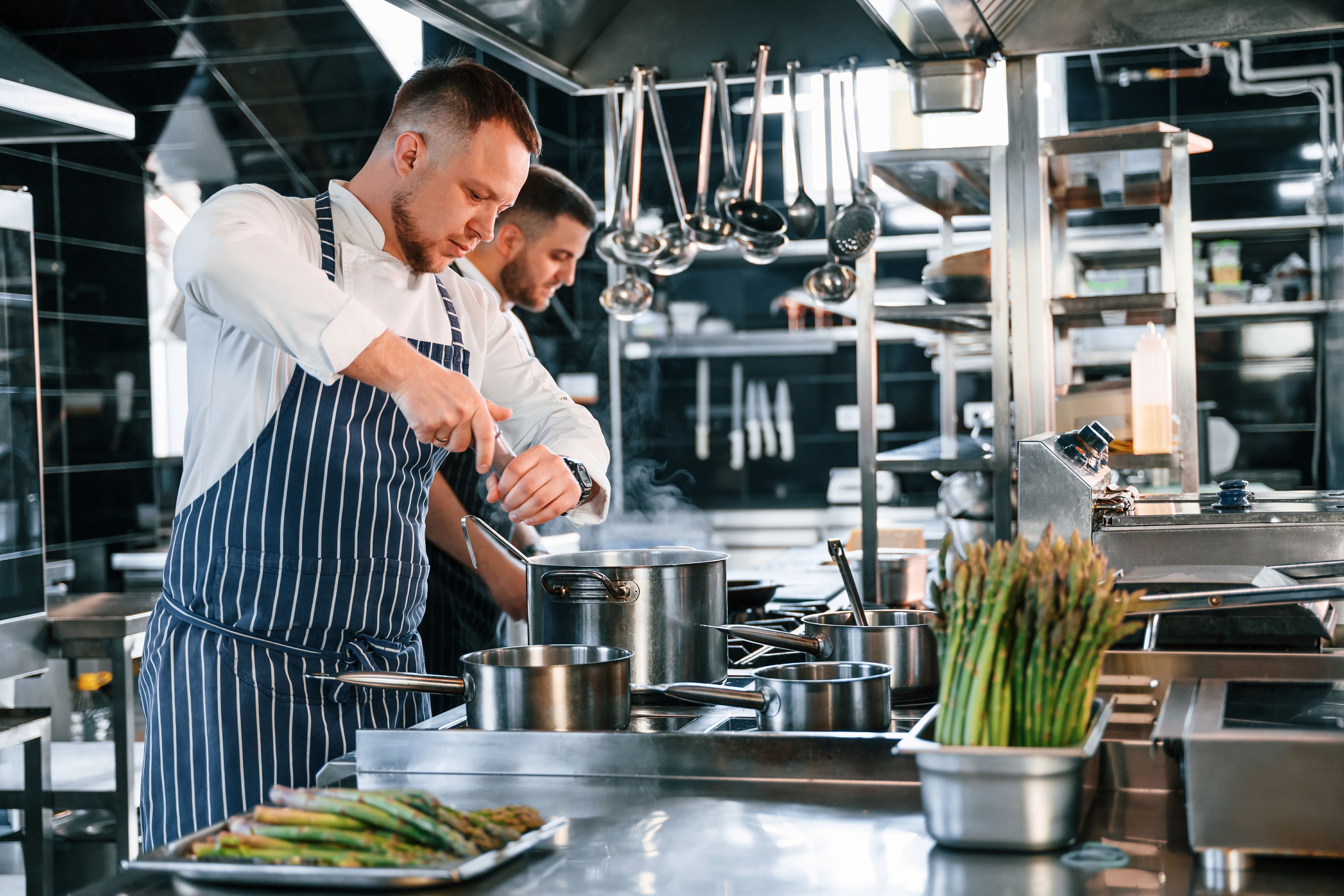 professional chef team preparing caterly catering food in commercial kitchen, bright lighting, food preparation